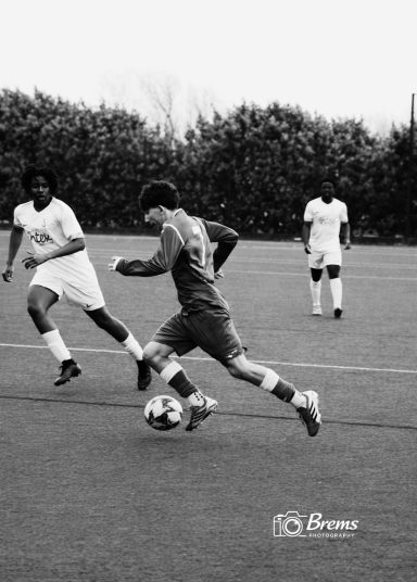 Footballers at a football match dribbling the ball on the field