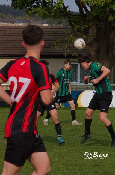 Footballers at a football match with the ball being headed
