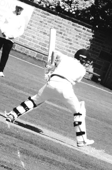 A man with a cricket bat on the cricket field at a cricket match