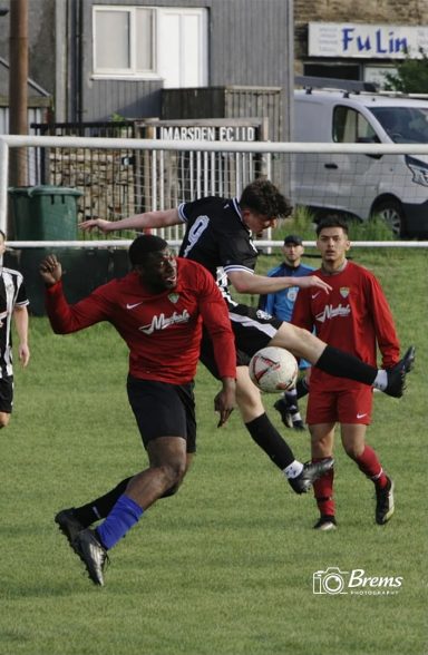 Footballers at a football match with the ball in the air