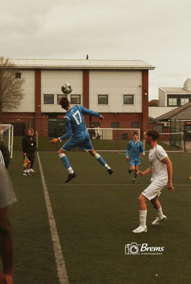 Footballers at a football match with the ball in the air