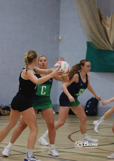 Netball players at a netball match passing the ball