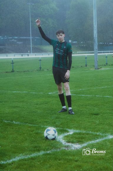 A football player with his arm up to take a free kick at a football match