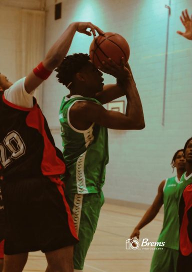 A young person holding up a basket ball ready for a shot at a basket ball match