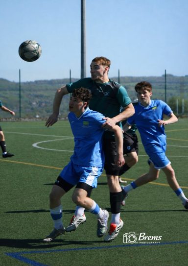 Footballers at a football match with the ball in the air