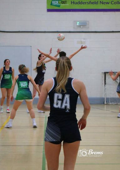 Netball players at a netball match with the ball in the air